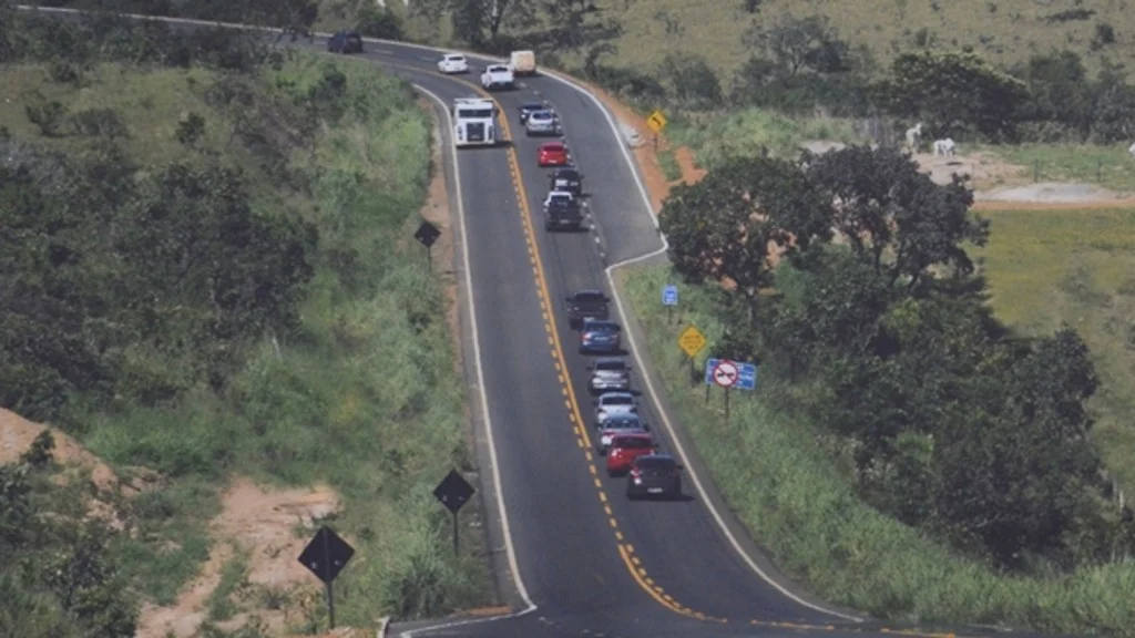 Vehicles on a two-lane highway climbing a rural hill